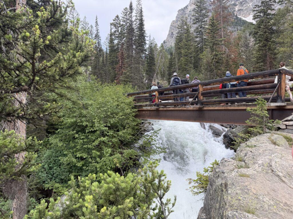 people standing on bridge over falls