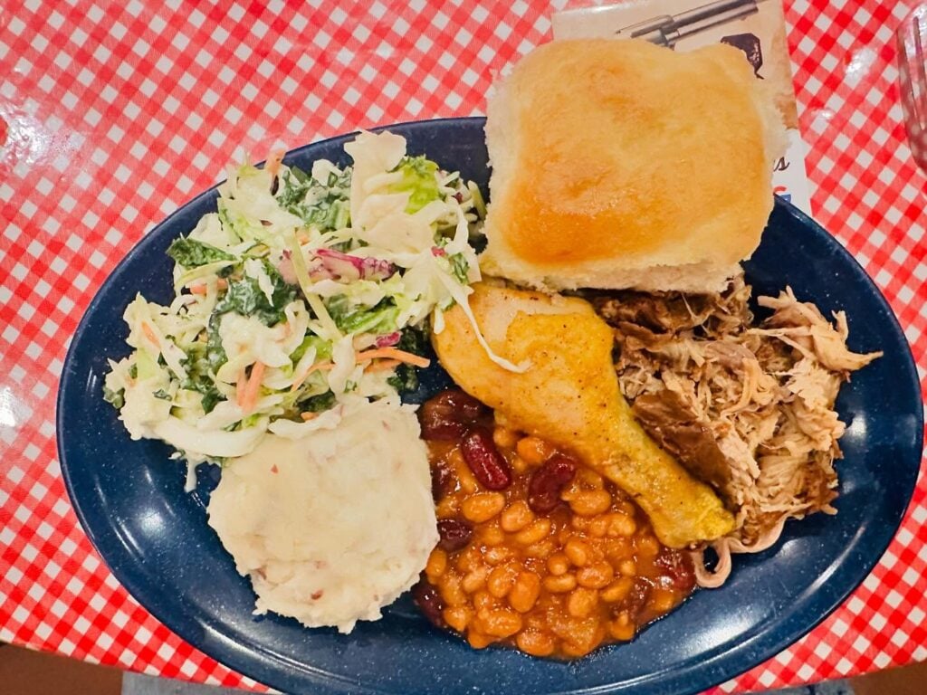 drumstick, roll, baked beans, pulled pork, mashed potatoes,and cole slaw on plate