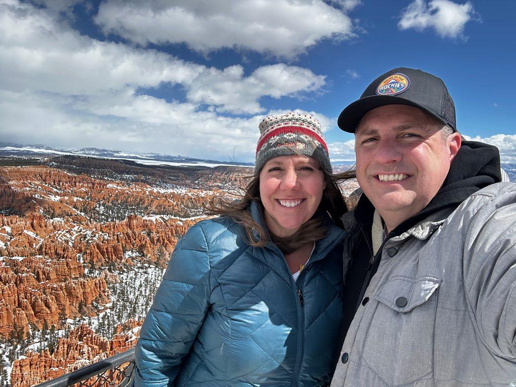 man and woman in front of hoodoos with snow