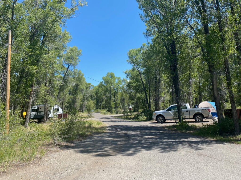 A road going through Gros Venture Campground that shows vehicles, tents, and trees