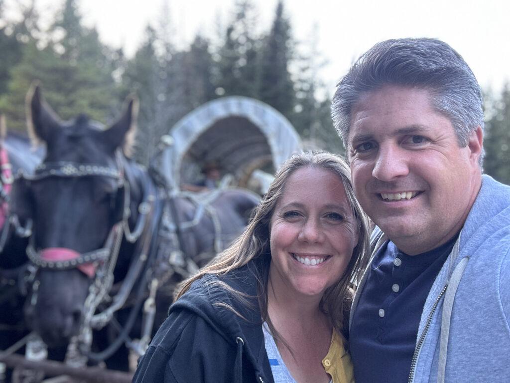 man and woman in front of horse and wagon