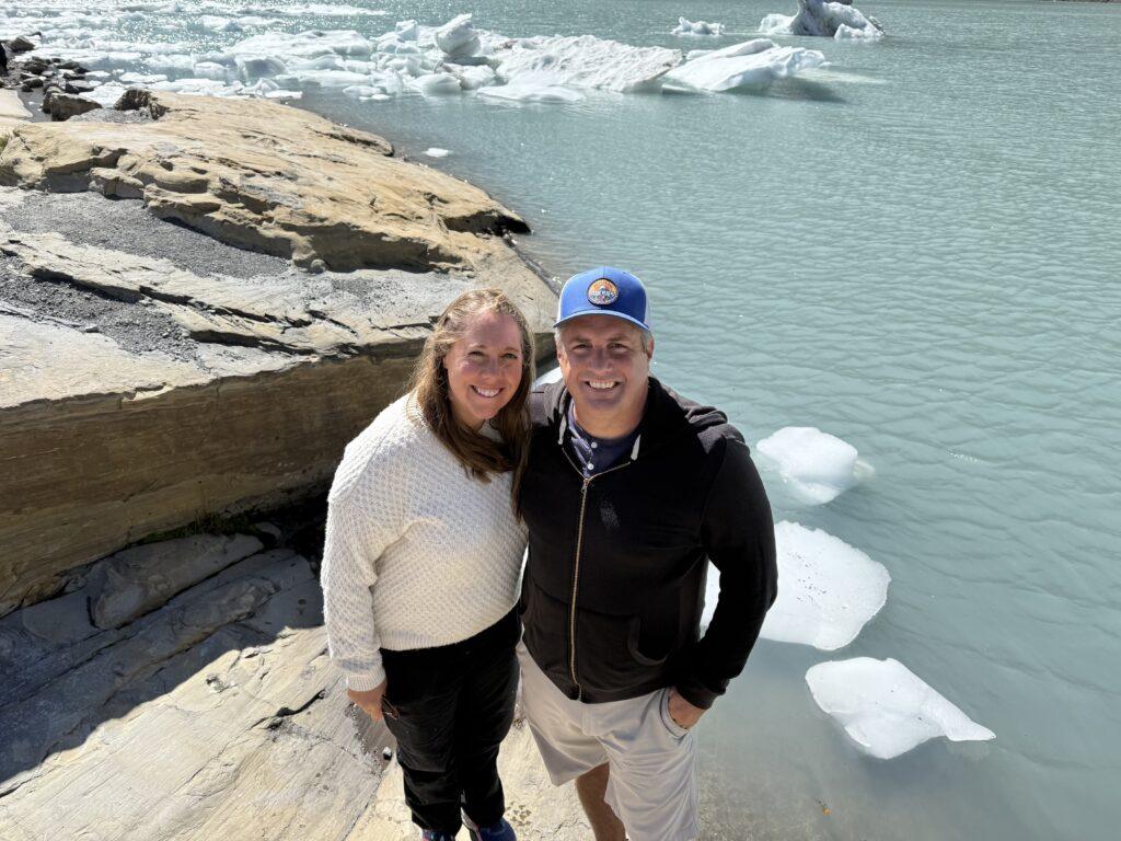 man and woman in front of glacial lake