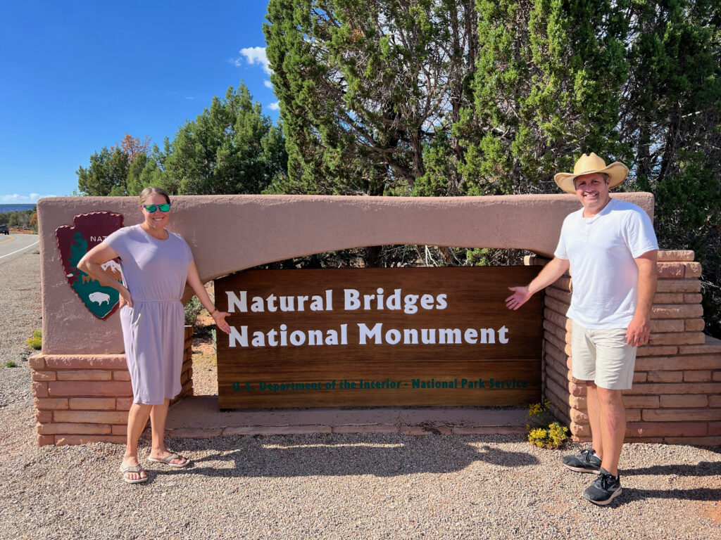 man and woman by Natural Bridges National Monument sign