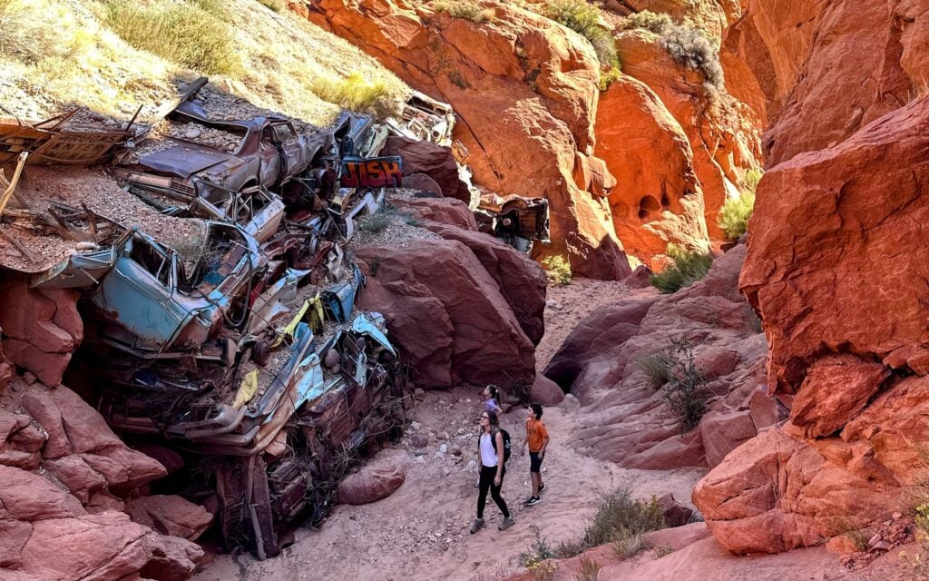 family looking up at stack of old cars in desert