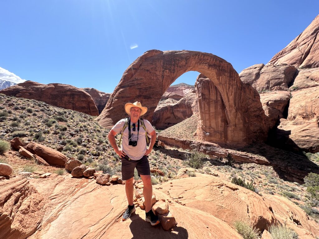 man standing in front of red rock arch