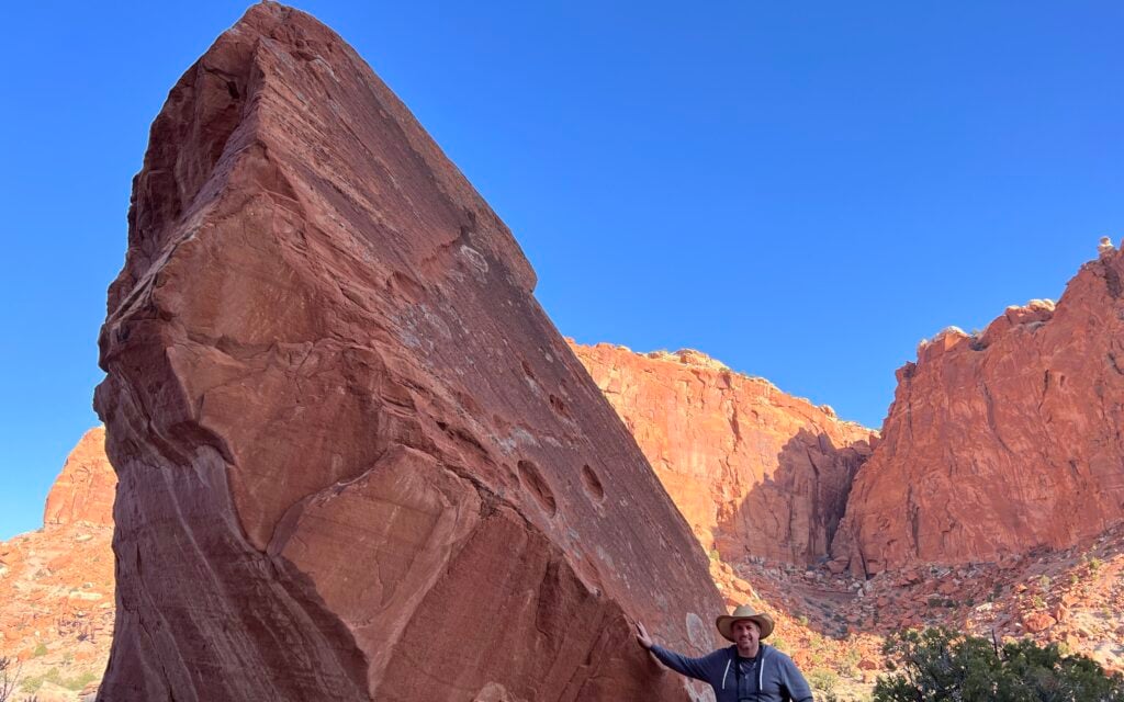 man standing near red rock formation