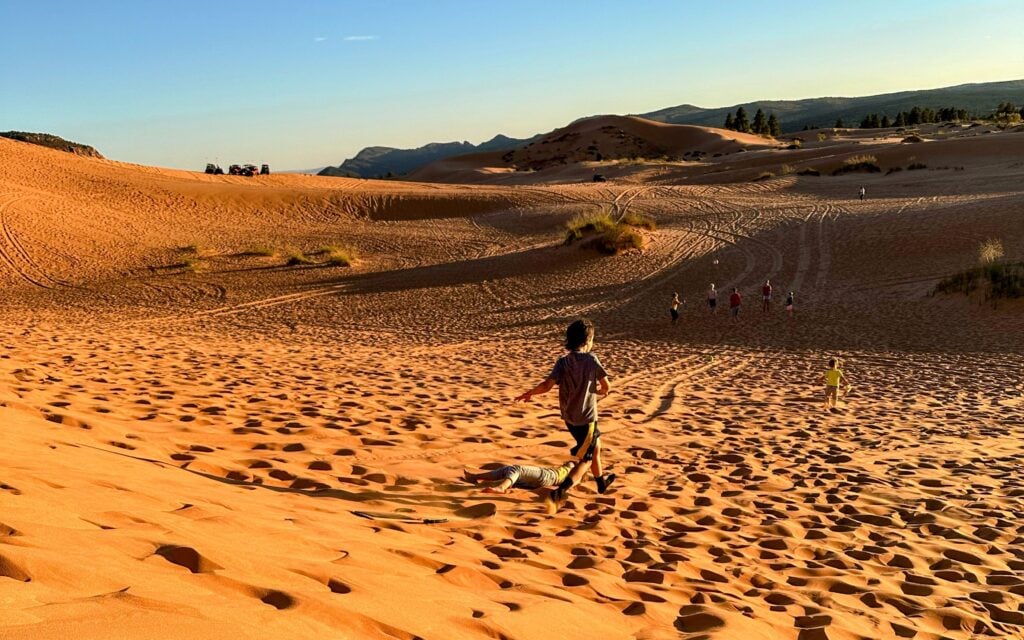 children running in sand at coral pink sand dunes