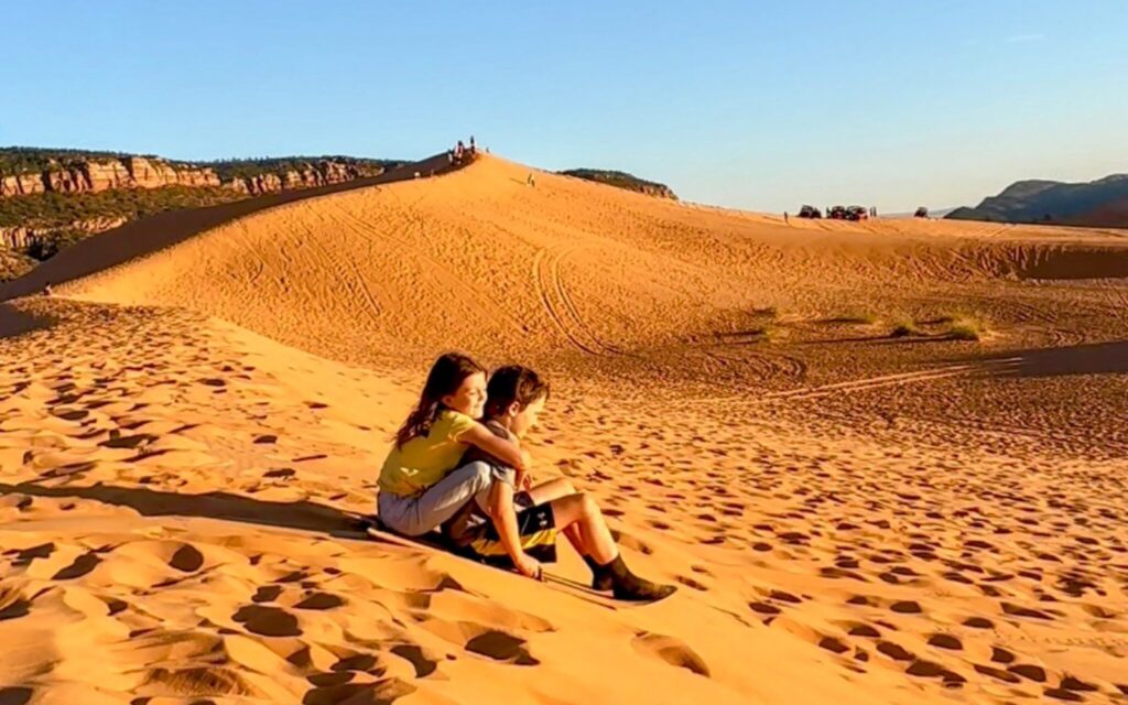 Two kids sitting in the sand at Coral Pink Sand Dunes