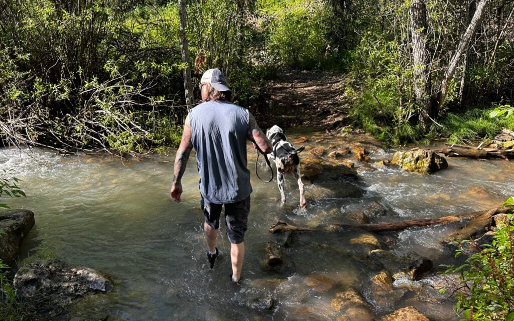 man and dog crossing the creek