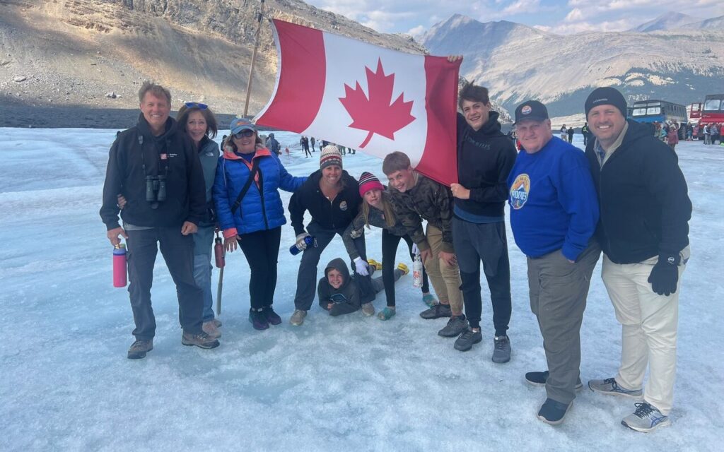People with Canadian flag standing on Athabasca Glacier