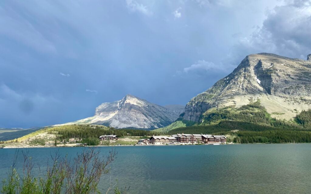 View of lake with Many Glacier Hotel on the other side of the lake with mountains in the background