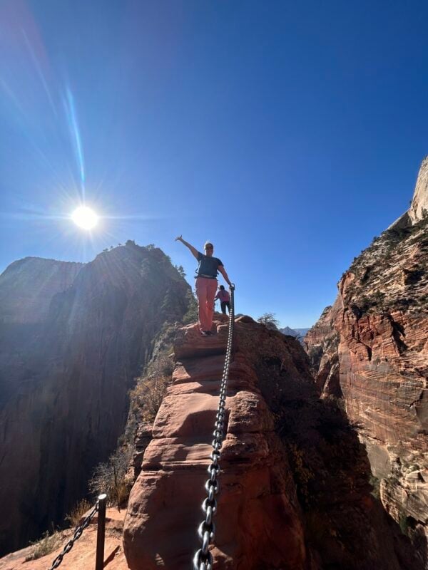 woman standing on cliff holding onto chain