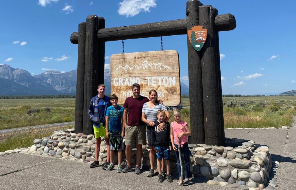 A family standing in front of the Grand Teton park sign