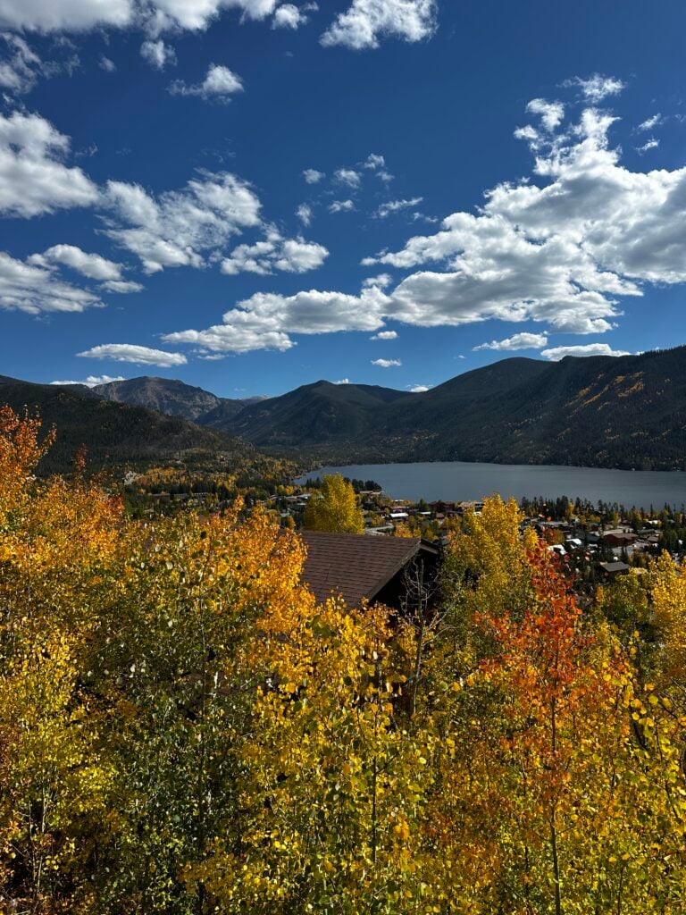 Trees with fall colors with a lake and mountains in the background