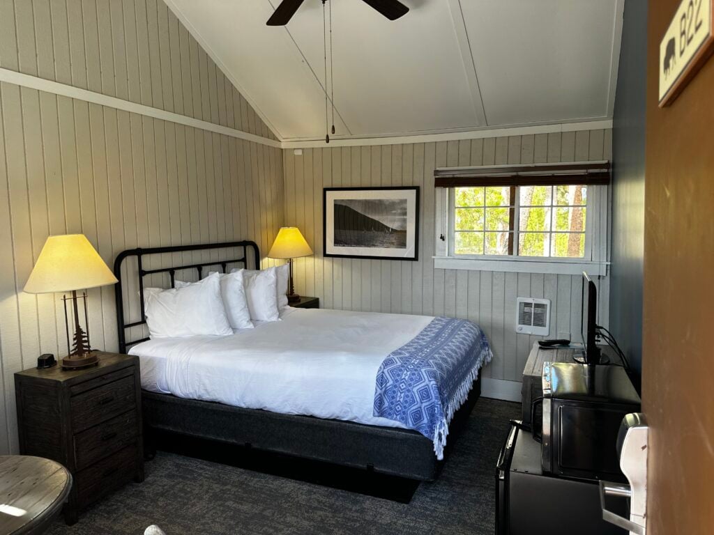 Inside of small cabin with a queen bed and lamps