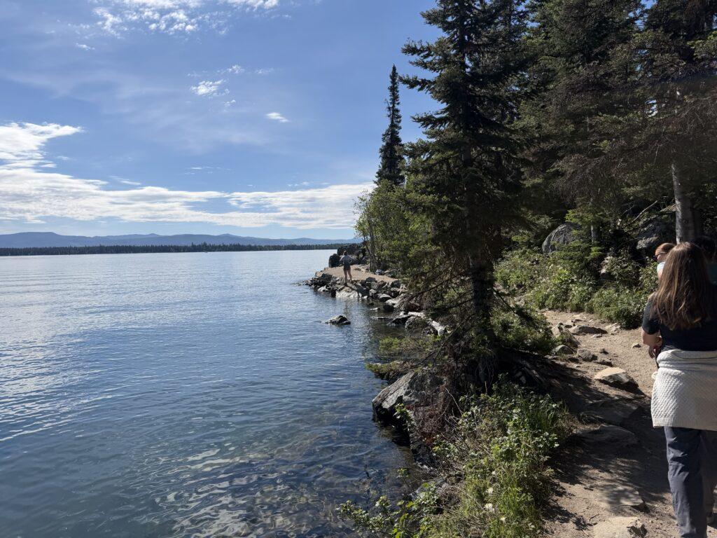 people hiking on trail next to lake