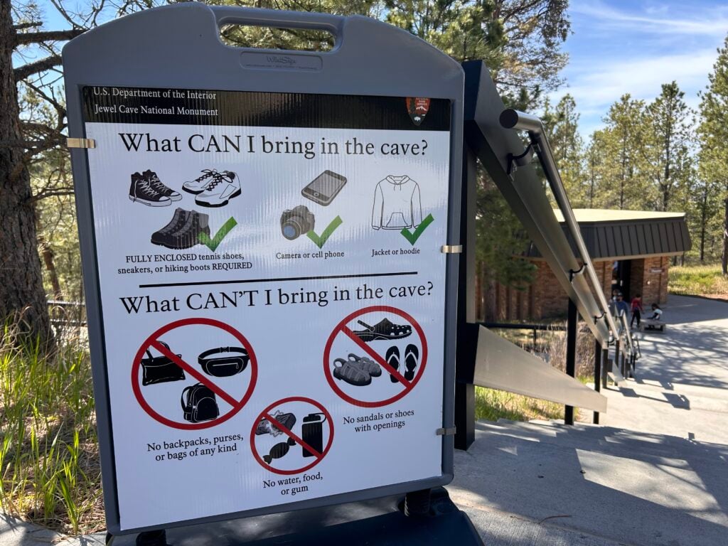 Sign saying what to bring in a cave: good shoes, camera, and jacket. Don't bring purses, backpacks, food, and sandals