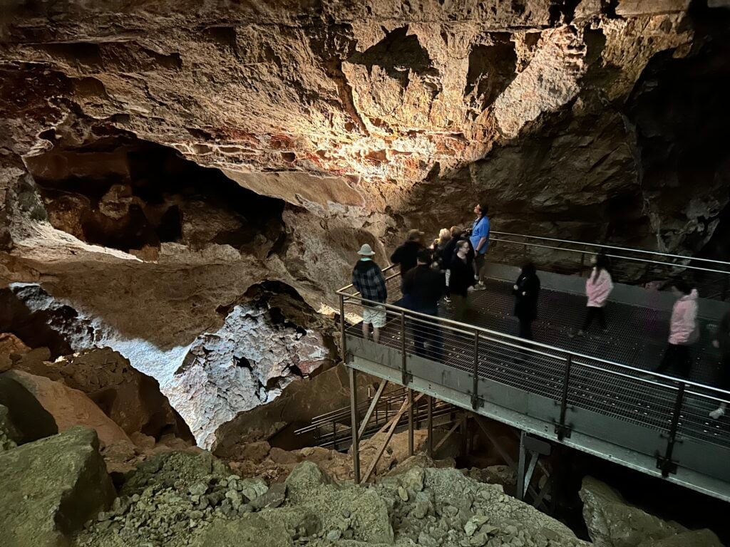 People standing on a metal platform inside a cave