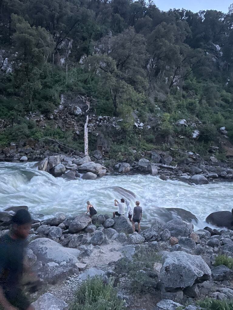 people standing near fast moving river