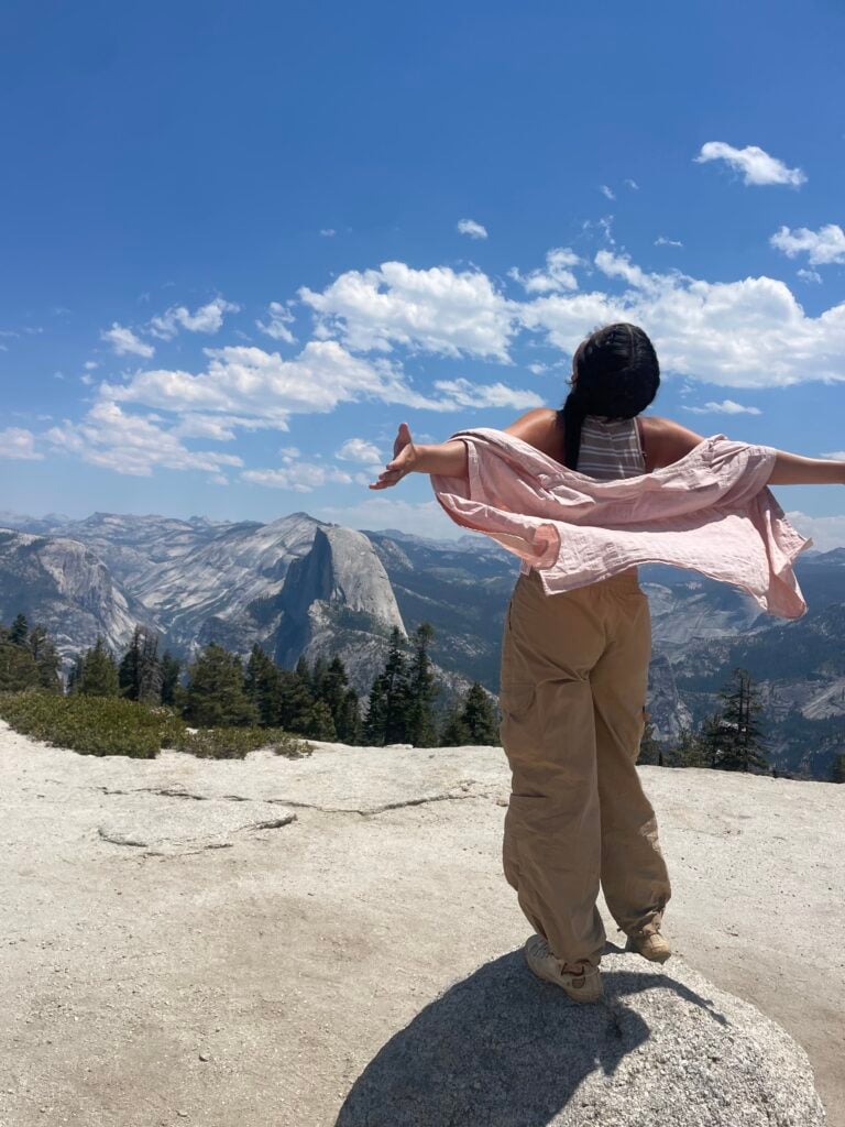 girls standing with arms out on cliff