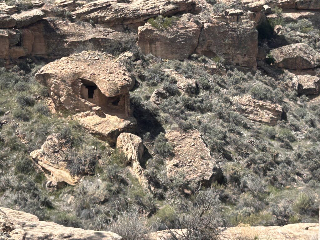 Ancient ruins made of stone with some over hanging rock of a boulder used as a roof