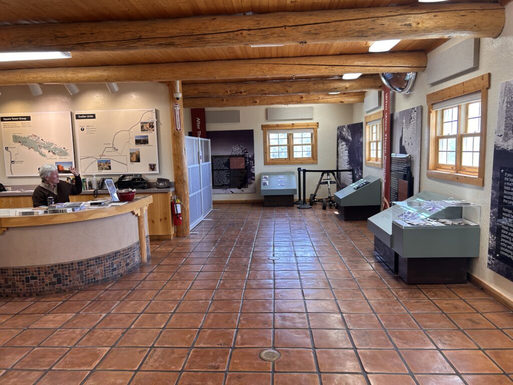 National park worker sitting at a desk inside of a visitor center. Maps are in the background