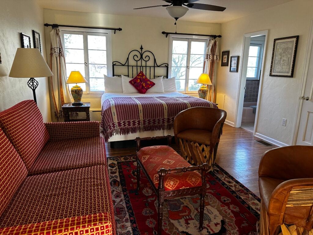 Queen bed with black metal frame with 2 windows in the background and a couch