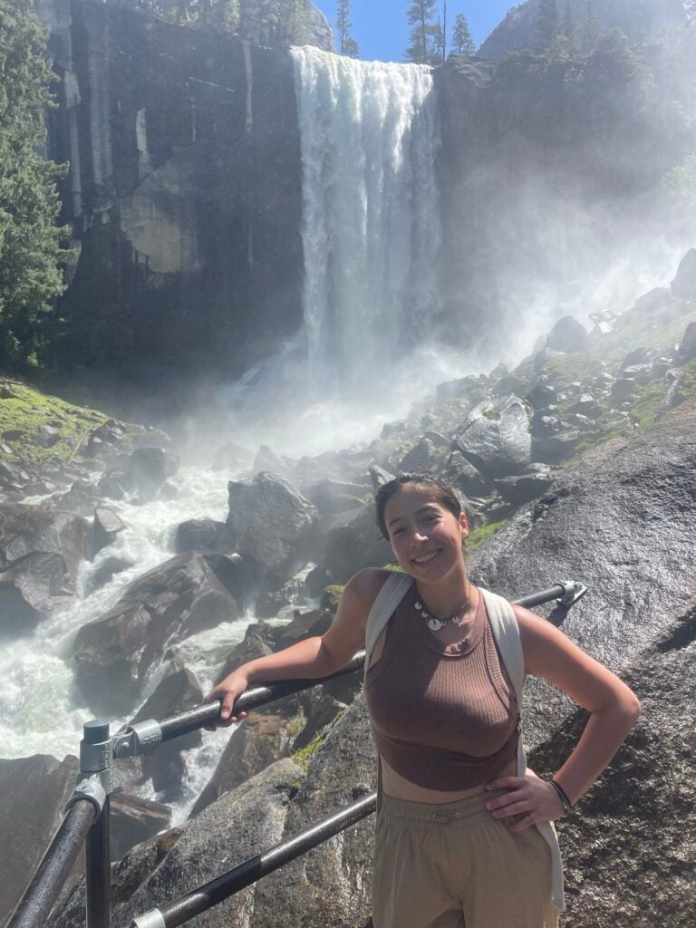 woman standing in mist of waterfall