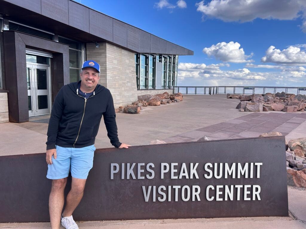 man standing infront of the Pikes Peak Summit Visitor Center