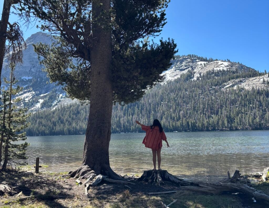 girl standing next to tree by lake