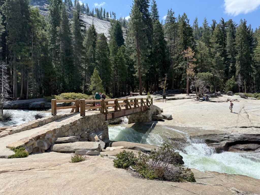 Wooden bridge over river with 2 people walking on it