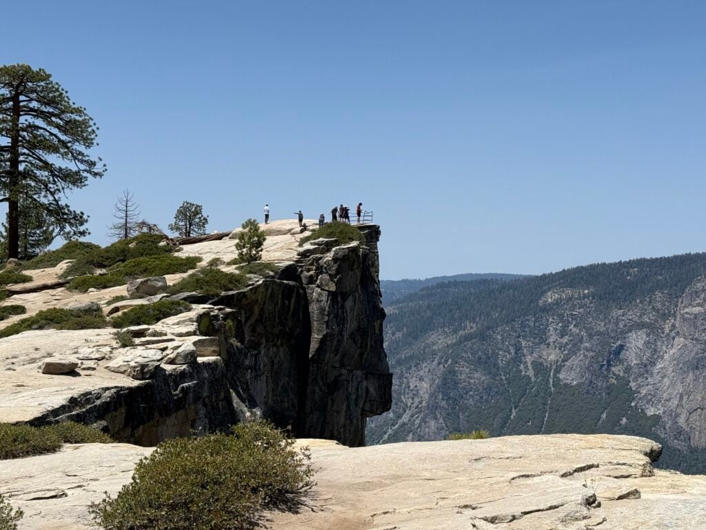 people standing on edge of cliff in distance