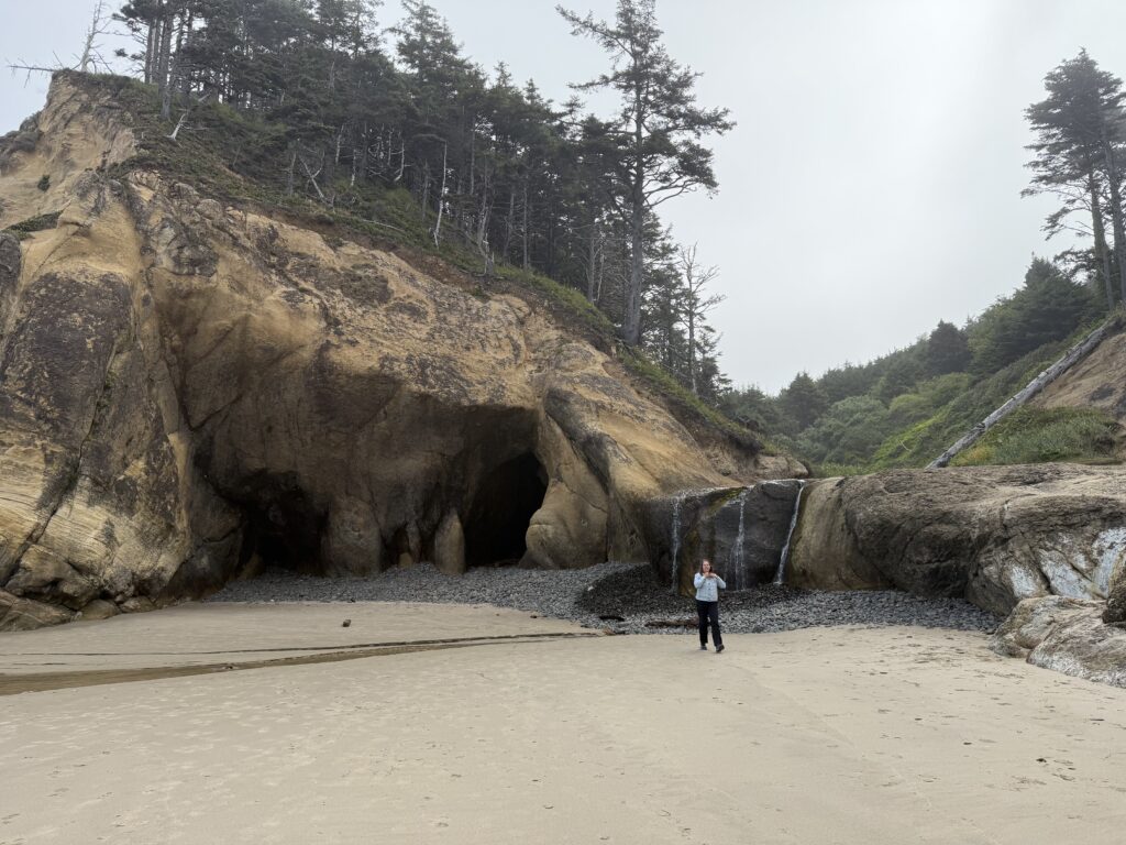 woman walking on beach in front of cave