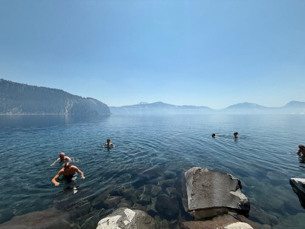 People swimming in clear, rocky water