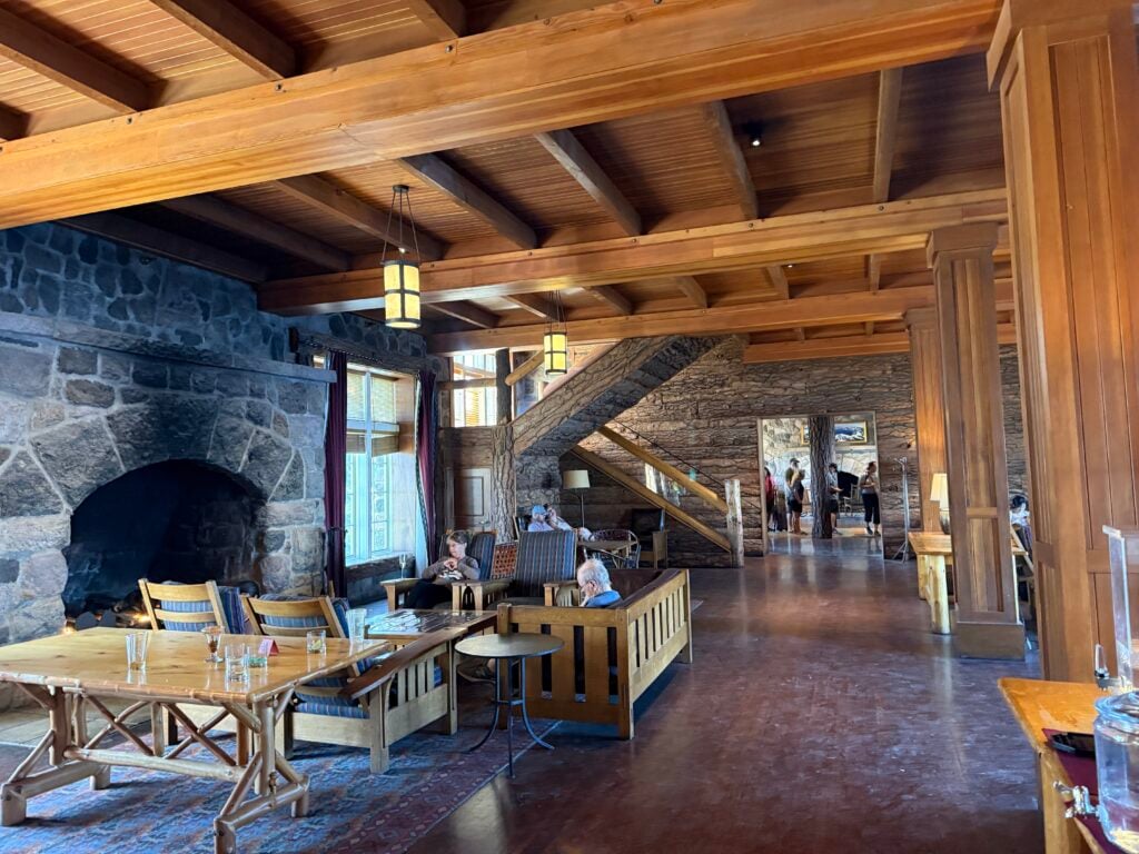 Lobby with fancy wood pillars, large stone fireplace, and tables and chairs