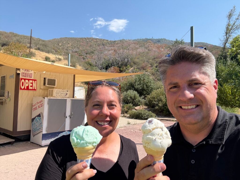 Man and woman eating an ice cream cone with the mountains in the background