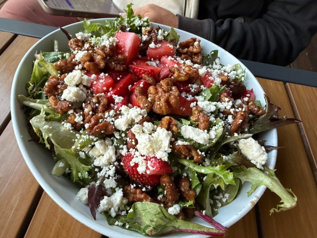Green salad topped with strawberries, pecans, and feta cheese