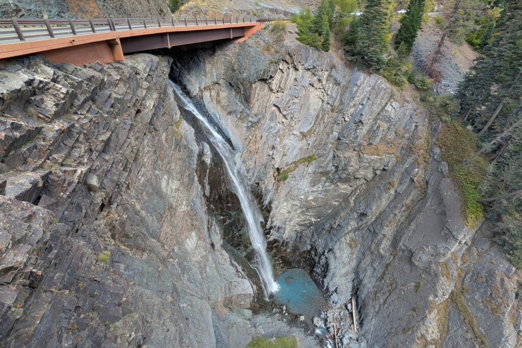 looking down on waterfall coming under a highway bridge