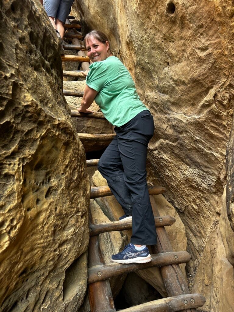 woman climbing ladder to cliff dwelling in Mesa Verde