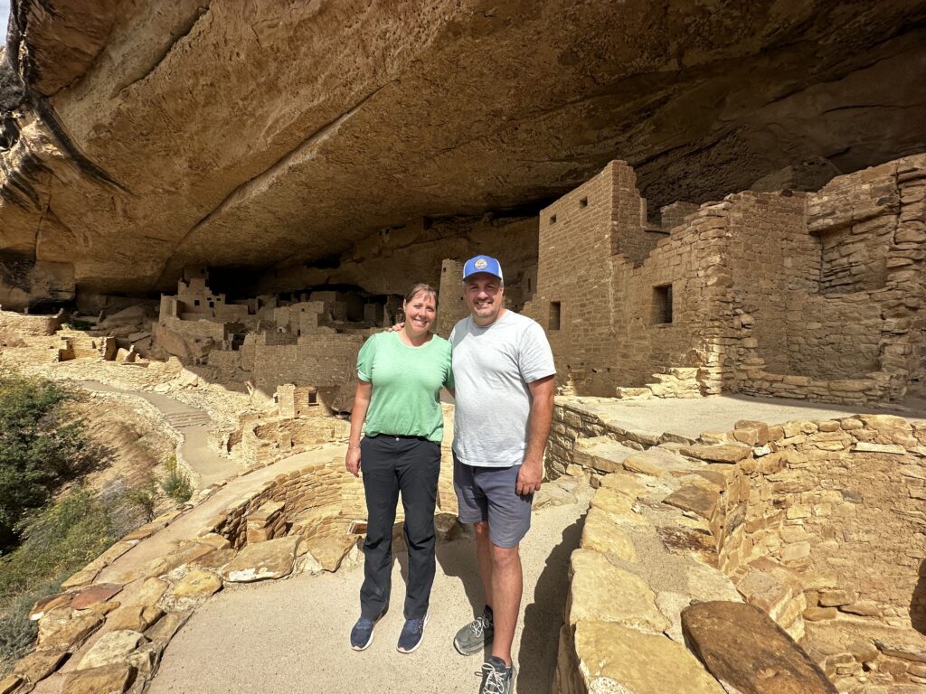 man and woman in front of cliff dwelling