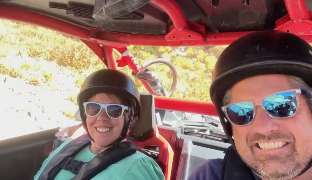 man and woman with helmets in offroad vehicle