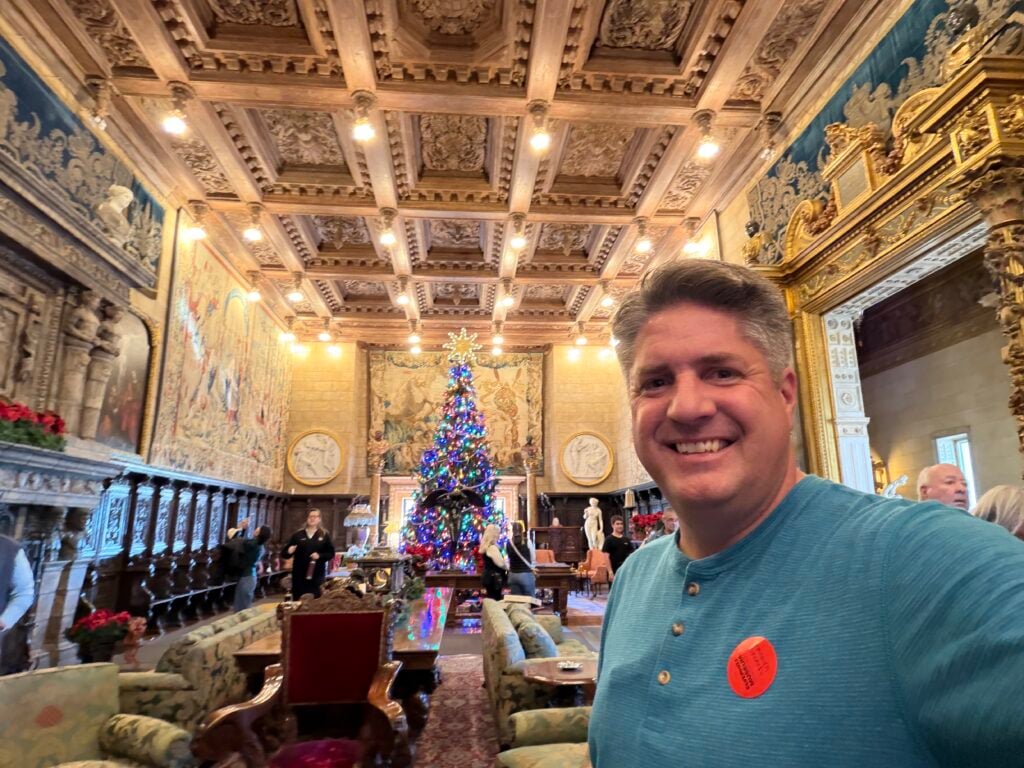 man inside lobby of Hearst Castle with Christmas Tree in background