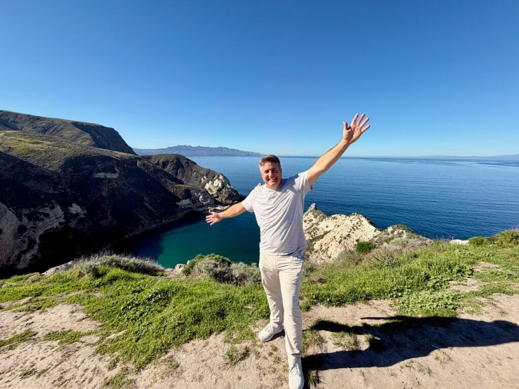man on edge of cliff with ocean in background