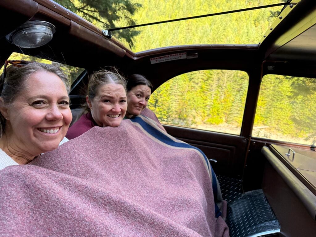 women covered in blanket in red bus in Glacier np
