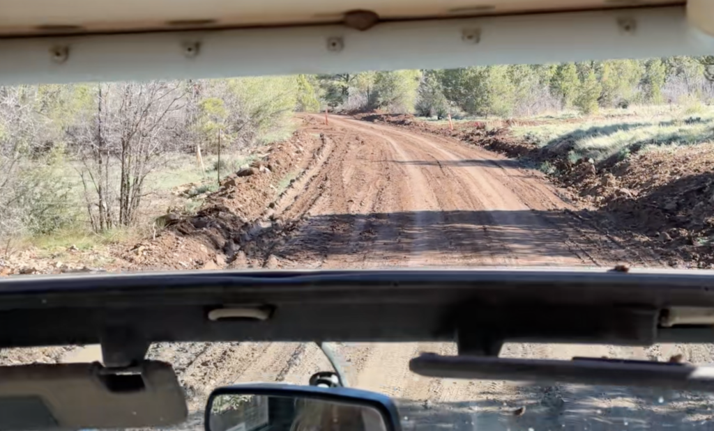 view of muddy road through windshield of jeep