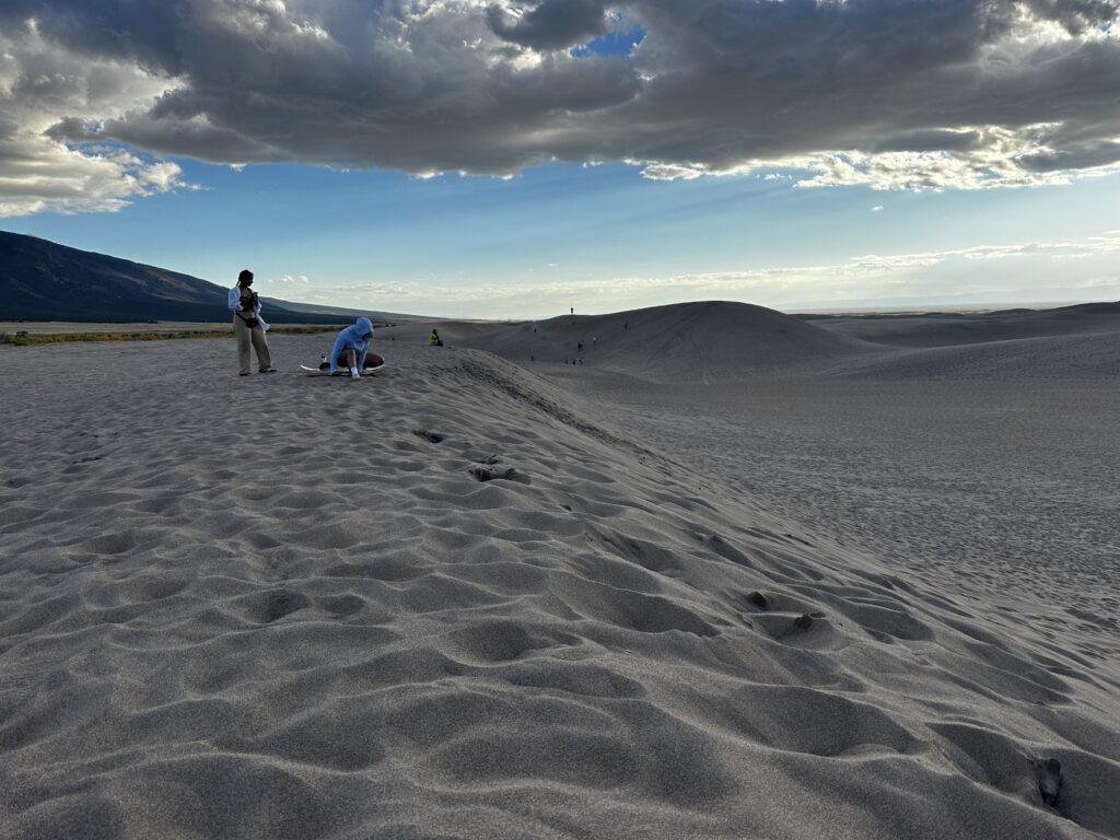 people sandboarding at the sand dunes