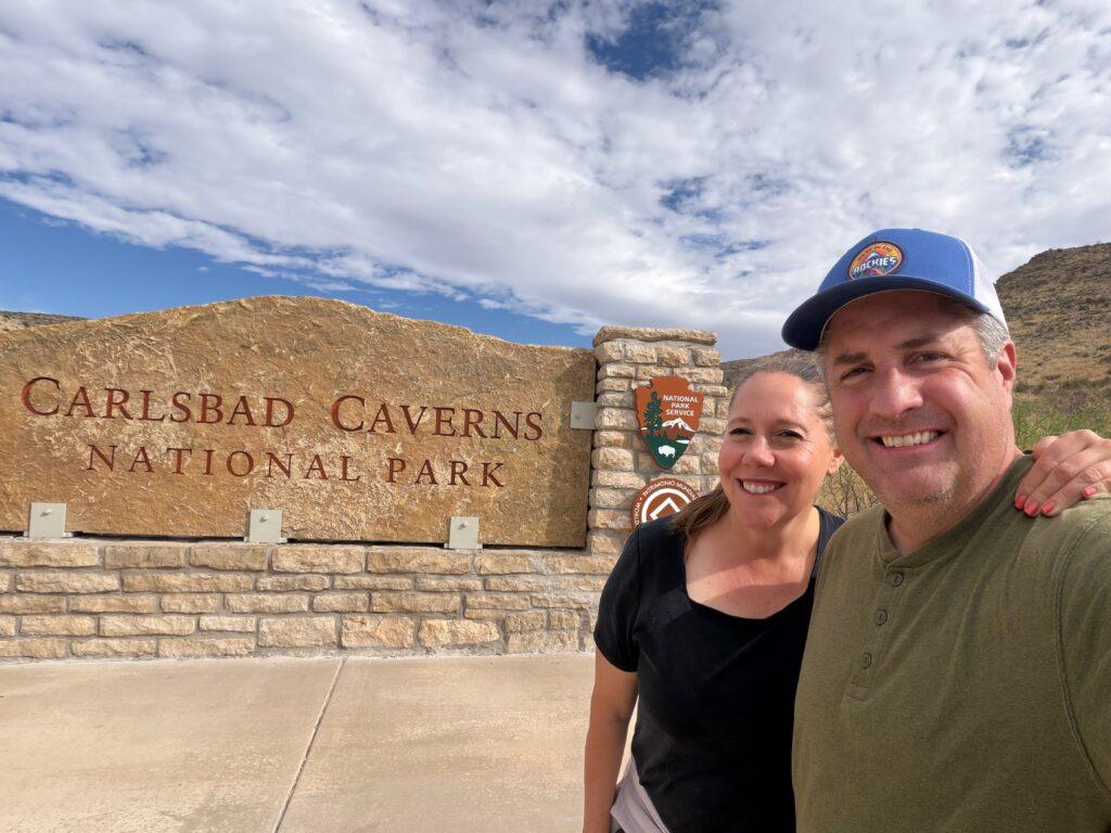 man and woman in front of Carlsbad Caverns National Park sign