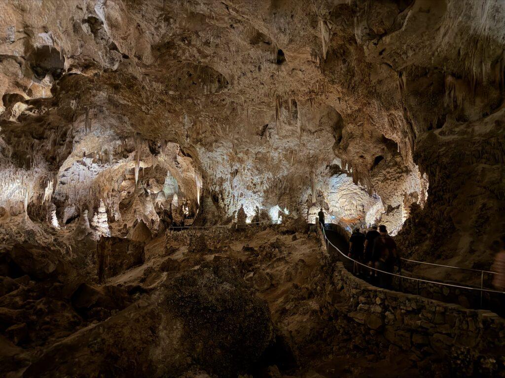 people walking along path through large room in cave
