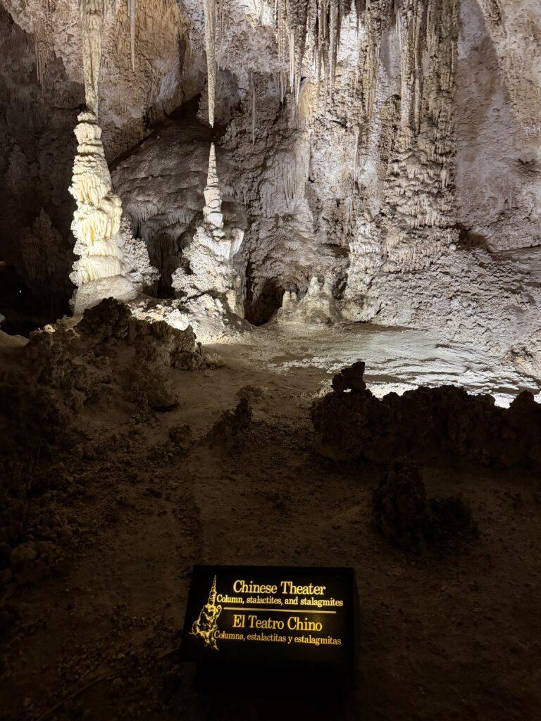 stalactites and stalagmites in cave with illuminated sign