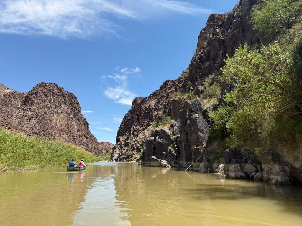 people in canoe going down muddy river